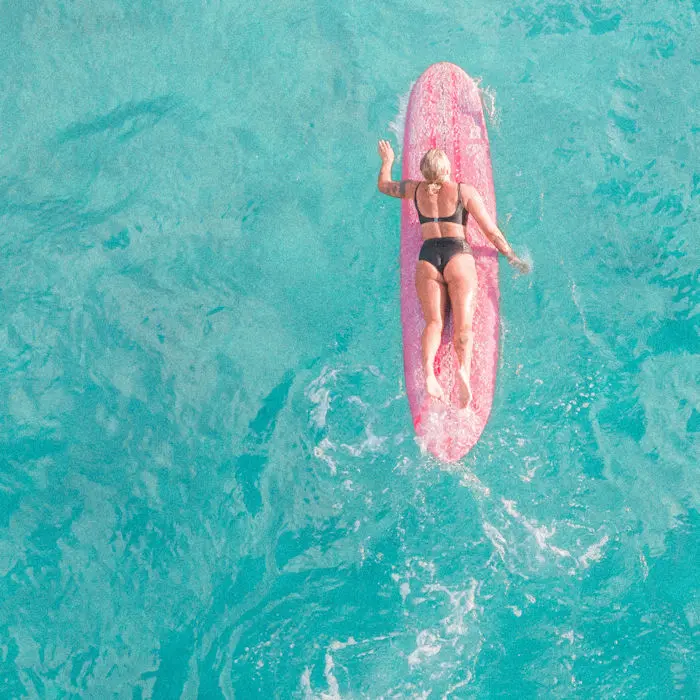 Woman lying on surfboard on blue sea